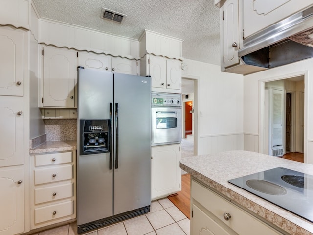 kitchen with tasteful backsplash, appliances with stainless steel finishes, a textured ceiling, and light tile patterned flooring