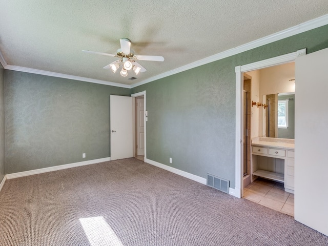 unfurnished bedroom featuring ornamental molding, connected bathroom, a textured ceiling, light carpet, and ceiling fan