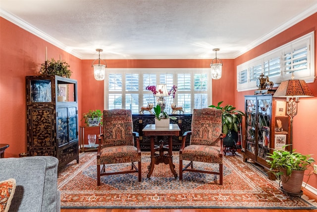 sitting room featuring wood-type flooring, a textured ceiling, crown molding, and a notable chandelier