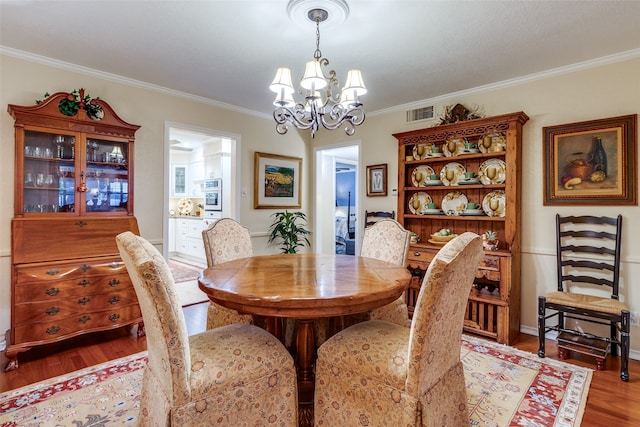 dining room with a chandelier, wood-type flooring, and ornamental molding