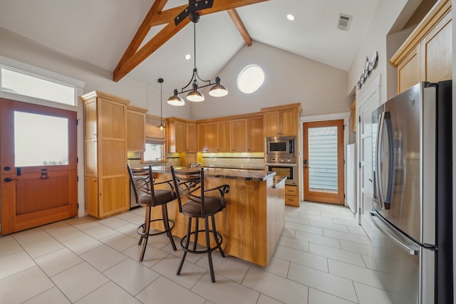 kitchen with a center island, beamed ceiling, pendant lighting, a kitchen bar, and appliances with stainless steel finishes