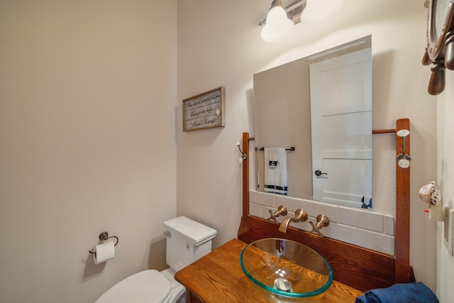 bathroom featuring vanity, toilet, and backsplash