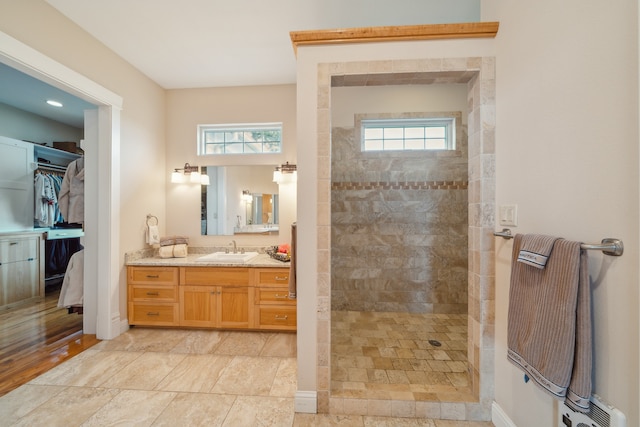 bathroom with tiled shower and vanity