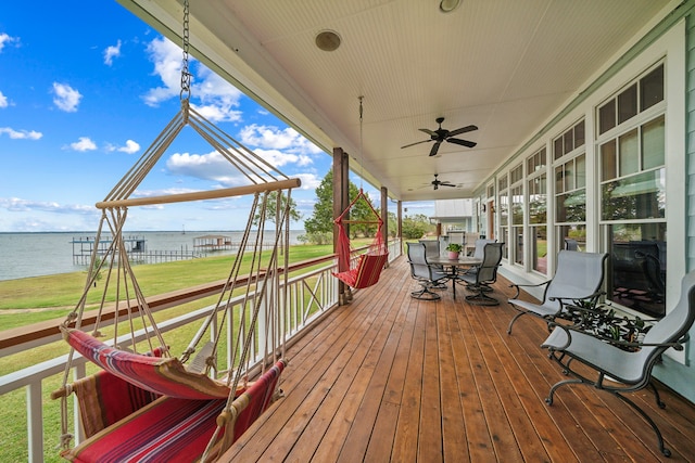 wooden terrace with covered porch, a yard, a water view, and ceiling fan