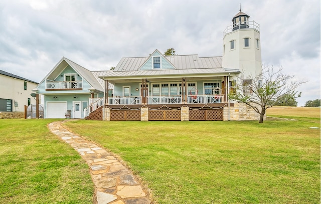 rear view of house featuring a porch, a balcony, a yard, and a garage