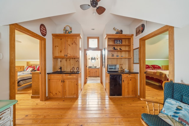 interior space with fridge, ceiling fan, vaulted ceiling, and light wood-type flooring