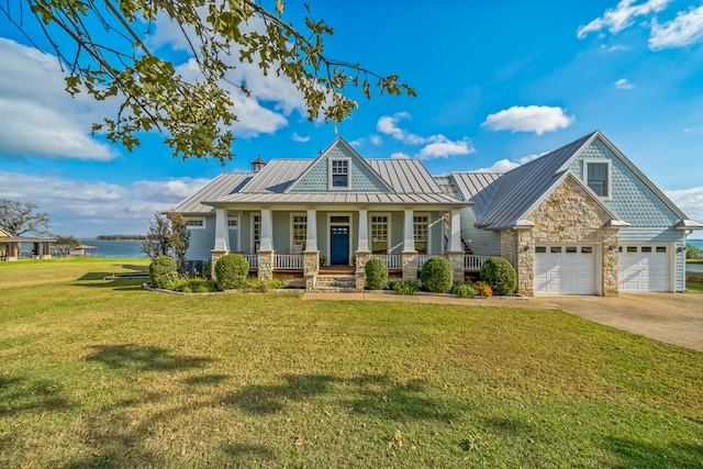 craftsman-style house with covered porch, a water view, a garage, and a front lawn