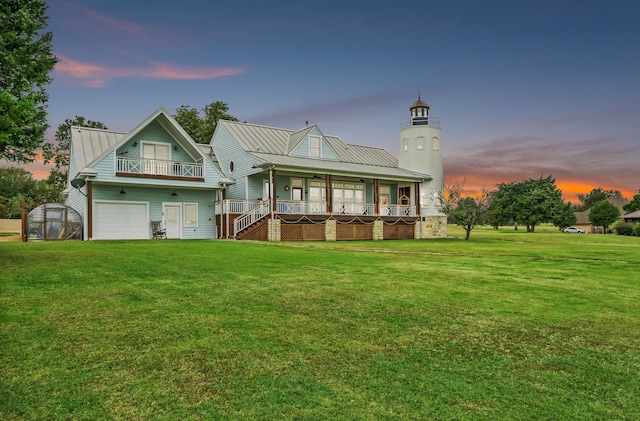 back house at dusk with a lawn, a porch, an outbuilding, and a balcony