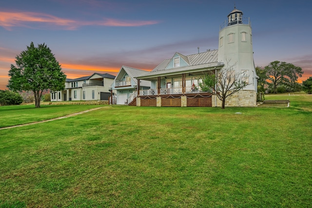 back house at dusk featuring a lawn, a porch, and a garage