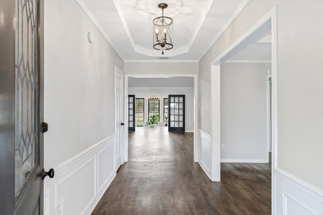 entryway with french doors, dark wood-type flooring, an inviting chandelier, ornamental molding, and a tray ceiling