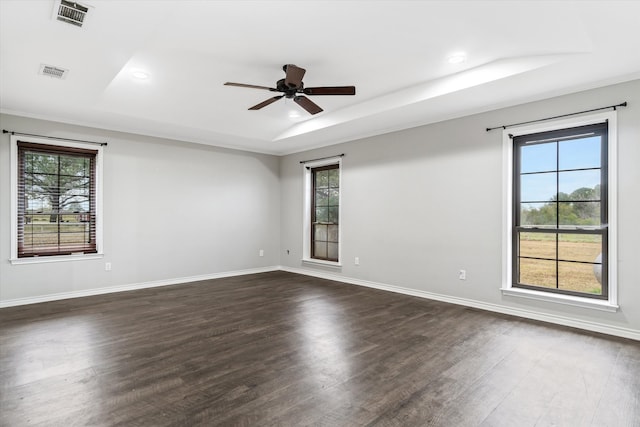 spare room featuring dark wood-type flooring, ceiling fan, and a raised ceiling