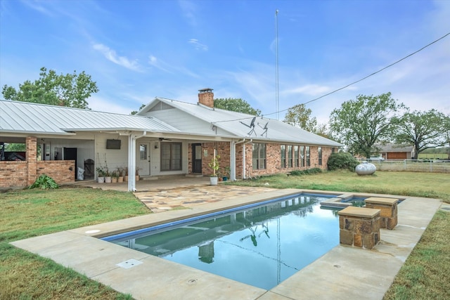 rear view of property featuring a patio area, a yard, and a swimming pool with hot tub