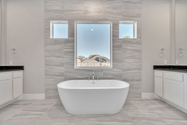 bathroom with a bathing tub, a wealth of natural light, and vanity