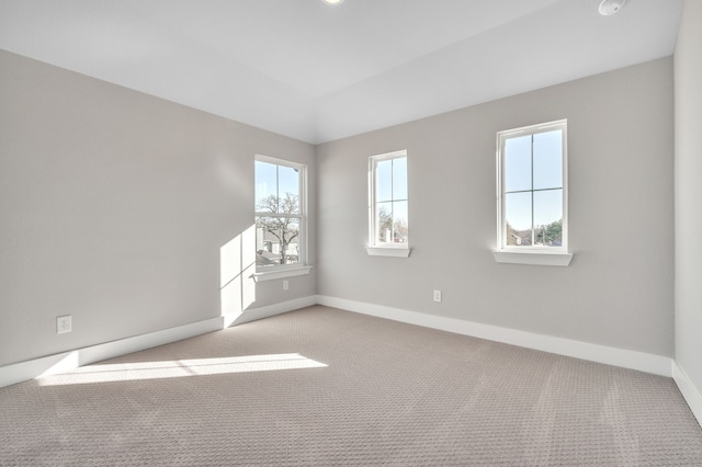 unfurnished room featuring lofted ceiling, plenty of natural light, and light carpet