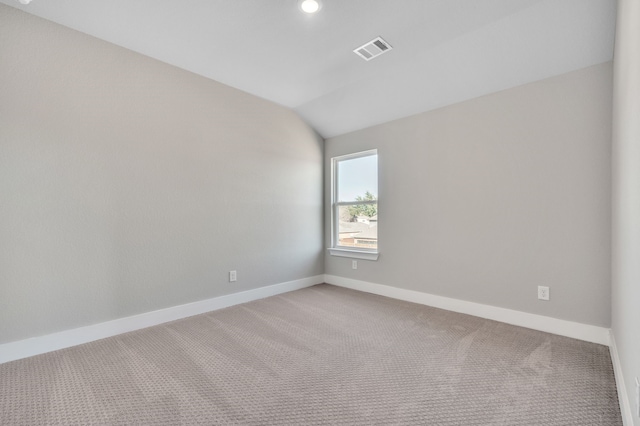 carpeted empty room with vaulted ceiling