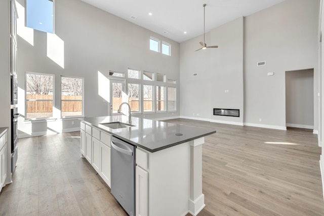 kitchen with sink, appliances with stainless steel finishes, a towering ceiling, an island with sink, and white cabinets