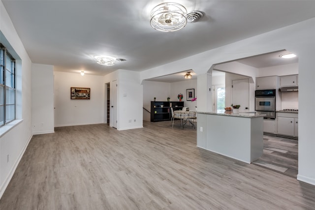 kitchen featuring light stone countertops, light hardwood / wood-style floors, and stainless steel gas stovetop