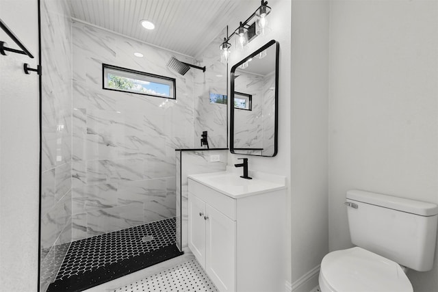 bathroom with vanity, toilet, and a tile shower