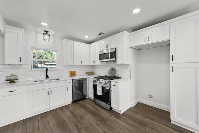 kitchen with sink, dark wood-type flooring, appliances with stainless steel finishes, white cabinetry, and decorative backsplash