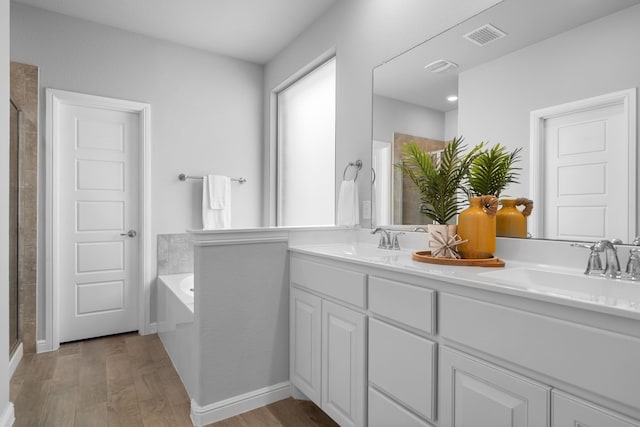 bathroom with hardwood / wood-style floors, shower with separate bathtub, and vanity