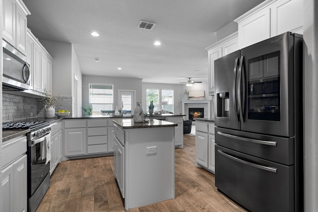 kitchen with a kitchen island, white cabinets, hardwood / wood-style floors, and stainless steel appliances