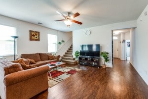 living room with dark hardwood / wood-style flooring, ceiling fan, and plenty of natural light