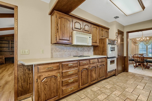 kitchen with light hardwood / wood-style floors, an inviting chandelier, white appliances, pendant lighting, and decorative backsplash