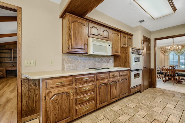 kitchen with hanging light fixtures, an inviting chandelier, backsplash, and white appliances