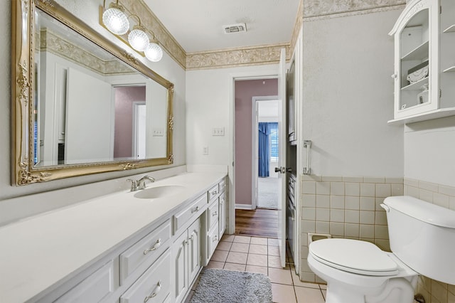 bathroom with tile walls, tile patterned flooring, vanity, and toilet