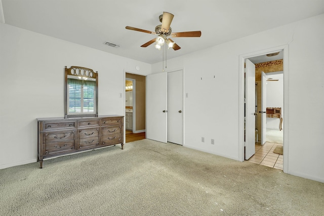 unfurnished bedroom with connected bathroom, light carpet, and ceiling fan