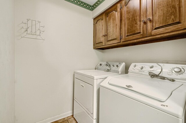 laundry area featuring light tile patterned floors, cabinets, and washing machine and clothes dryer