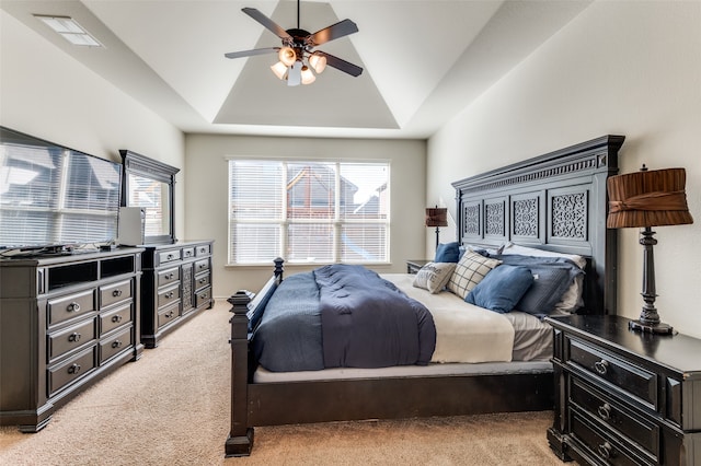 carpeted bedroom featuring ceiling fan, vaulted ceiling, and a tray ceiling