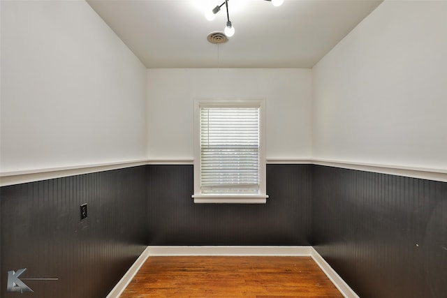 unfurnished room featuring wooden walls