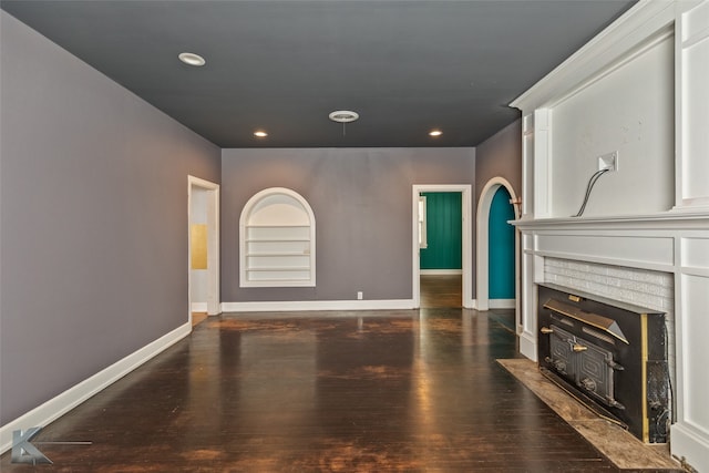 unfurnished living room with a fireplace, dark hardwood / wood-style floors, and built in shelves