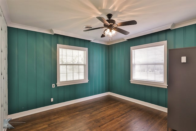 empty room featuring ornamental molding, dark hardwood / wood-style flooring, ceiling fan, and plenty of natural light