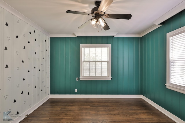 empty room featuring dark wood-type flooring, a wealth of natural light, ceiling fan, and ornamental molding