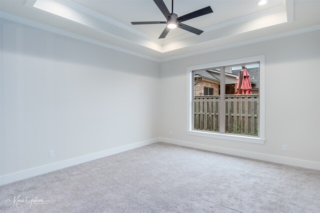 carpeted empty room with ceiling fan, ornamental molding, and a tray ceiling