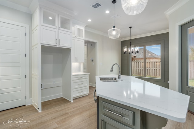 kitchen with light stone counters, sink, an island with sink, and white cabinets