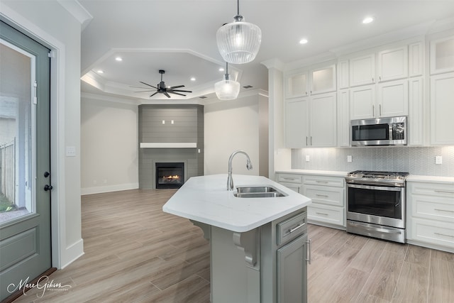 kitchen featuring stainless steel appliances, white cabinetry, a center island with sink, and sink