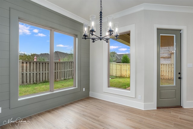 unfurnished dining area with light hardwood / wood-style floors, a healthy amount of sunlight, and a notable chandelier