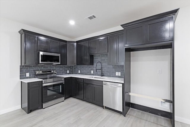 kitchen featuring sink, decorative backsplash, light hardwood / wood-style flooring, and appliances with stainless steel finishes