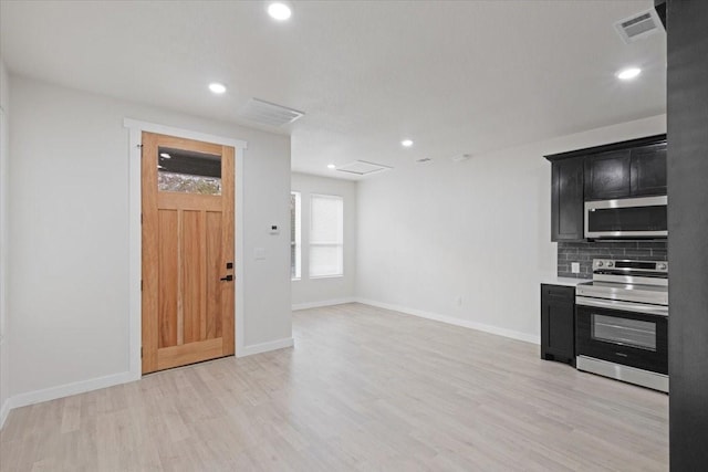 kitchen featuring appliances with stainless steel finishes, backsplash, and light wood-type flooring