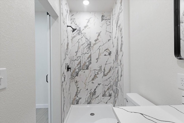 bathroom featuring tiled shower and toilet