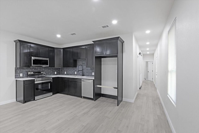 kitchen with a barn door, tasteful backsplash, appliances with stainless steel finishes, and light hardwood / wood-style flooring