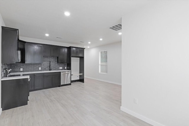 kitchen featuring backsplash, sink, dishwasher, and light wood-type flooring