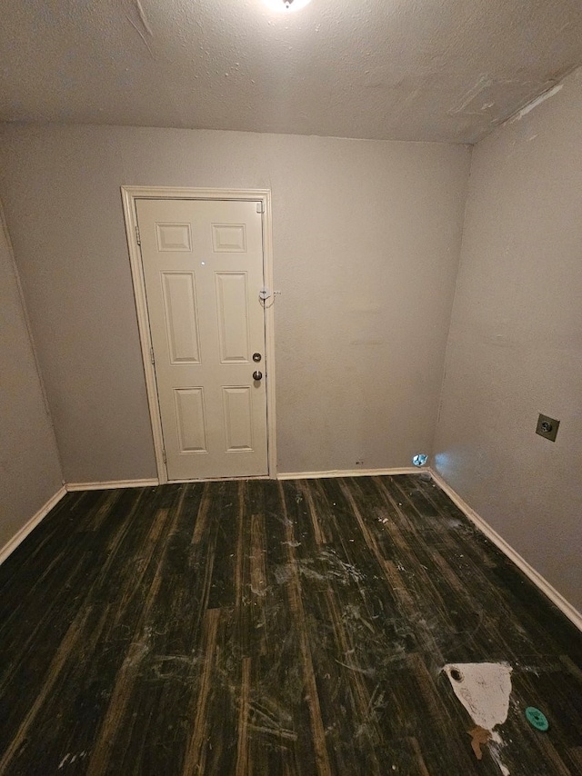 spare room featuring dark wood-type flooring and a textured ceiling