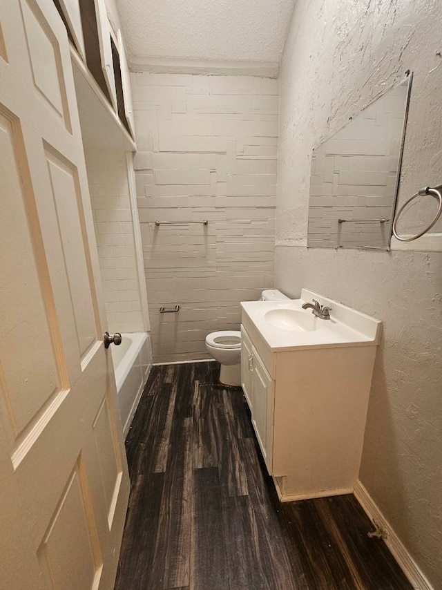 full bathroom with wood-type flooring, toilet,  shower combination, a textured ceiling, and vanity