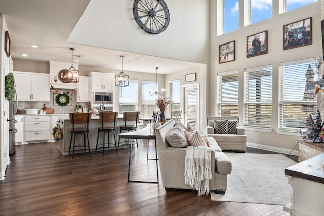 living room featuring dark hardwood / wood-style floors, a high ceiling, and an inviting chandelier