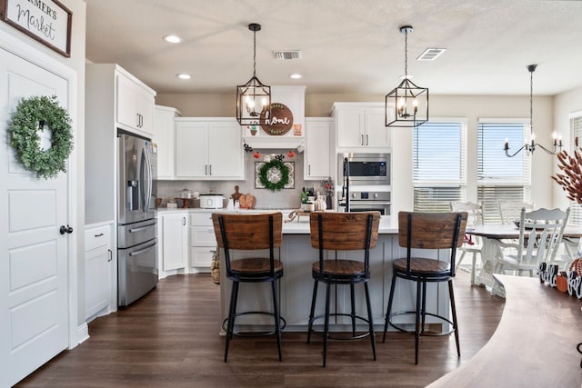 kitchen with appliances with stainless steel finishes, decorative light fixtures, and white cabinets