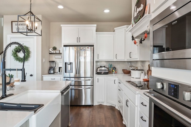 kitchen featuring stainless steel appliances, dark hardwood / wood-style flooring, hanging light fixtures, an inviting chandelier, and white cabinets